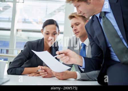 Discuter de leur stratégie financière. un groupe d'hommes d'affaires qui examine les documents financiers. Banque D'Images