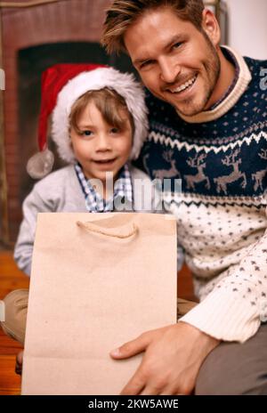 L'heure des cadeaux. Un garçon et son père assis avec un cadeau la veille de Noël. Banque D'Images