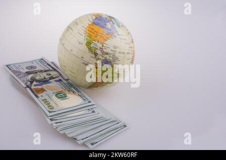 Billets en dollar américain par le côté d'un modèle globe on white background Banque D'Images