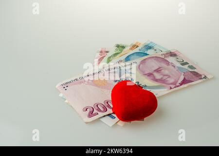 Billets Lire turque par le côté d'un objet en forme de coeur de couleur rouge sur fond blanc Banque D'Images