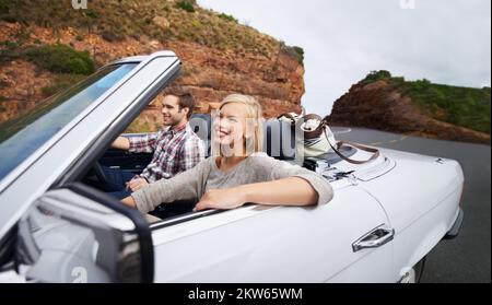 Croisière avec la capote abaissée. un jeune couple séduisant qui va faire le tour des montagnes dans leur voiture d'époque. Banque D'Images