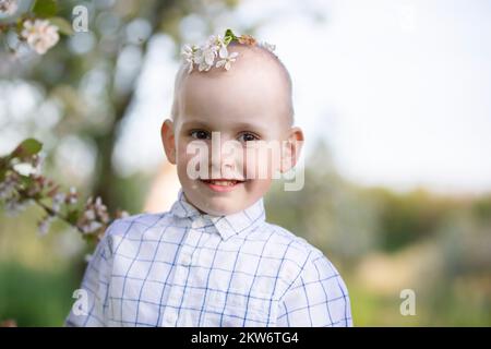 Un enfant heureux dans un jardin de printemps en pleine floraison se réjouit, sourit. Banque D'Images