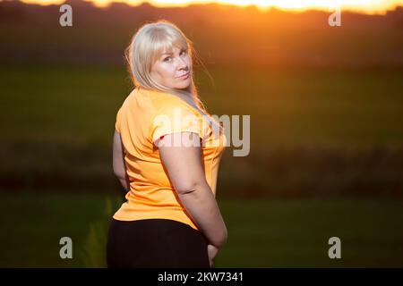 Portrait d'une femme européenne d'âge moyen dans un survêtement, posant pour l'appareil photo, relaxant. Femme excitée en surpoids dans un tracksuit tendance se reposant après e Banque D'Images