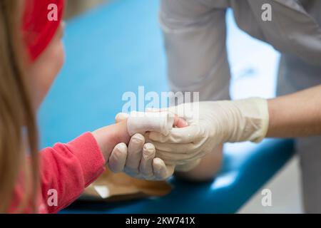 Les mains du médecin bandent le doigt douloureux avec un bandage de l'enfant.Blessure et blessure au doigt chez les enfants Banque D'Images