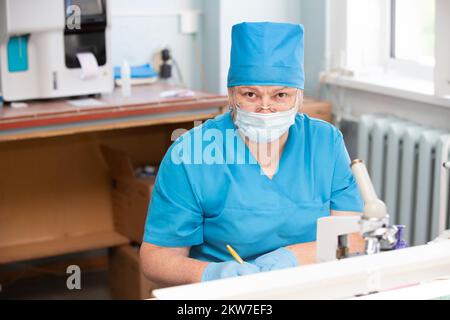 Une femme âgée médecin dans un masque médical et des lunettes regarde la caméra. Banque D'Images