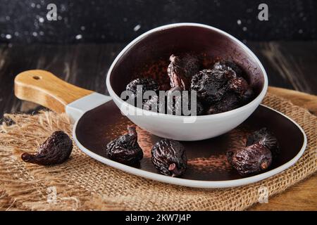 Figues de mission séchées dans un bol en verre sur toile de fond en bois. Banque D'Images