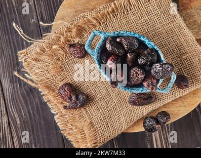 Figues de mission séchées dans un bol en verre sur toile de fond en bois. Pose à plat Banque D'Images