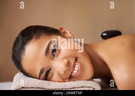 Détente en pierres chaudes. Une jeune femme ethnique reçoit un traitement de pierre chaude dans un spa. Banque D'Images