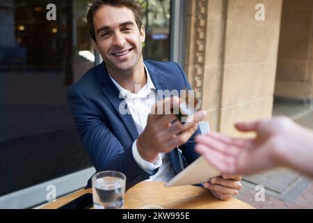 Placez-le sur le plastique. Un jeune homme d'affaires payant son café avec une carte de crédit au café. Banque D'Images