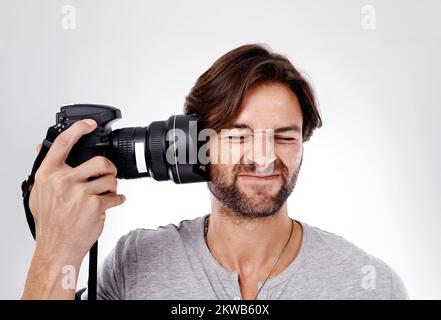 Prenez vos photos. Un jeune photographe qui appuie son appareil contre l'oreille. Banque D'Images