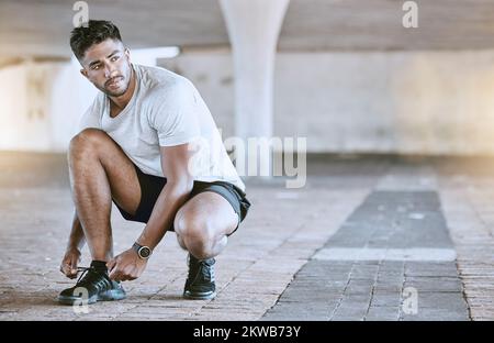 Fitness, course et exercice, un homme qui va courir en ville. Motivation, cardio et entraînement, un coureur laçage ses chaussures de sport avant un extérieur Banque D'Images