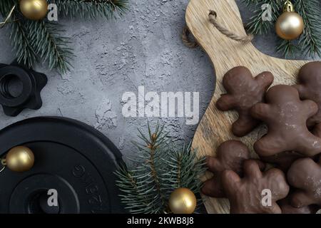 Biscuits de Noël au pain d'épice au chocolat, branches d'arbre, assiette de poids à haltères. Fitness vacances saison hiver régime composition. Concept d'entraînement de gym. Banque D'Images