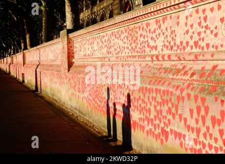 Mur commémoratif national Covid or brillant peu avant le coucher du soleil avec des ombres de passants sur la rive sud de la Tamise, Londres, Angleterre Banque D'Images