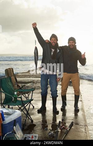 Il a lutté dur, mais j'ai gagné à la fin deux jeunes hommes pêchant sur un quai. Banque D'Images