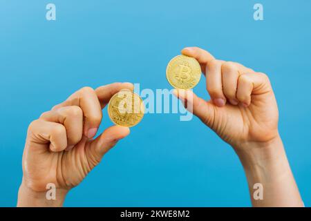 Gros plan des mains tenant des bitcoins d'or, espace de copie pour crypto-monnaie commerciale, argent numérique, investissement électronique. Prise de vue en studio isolée Banque D'Images