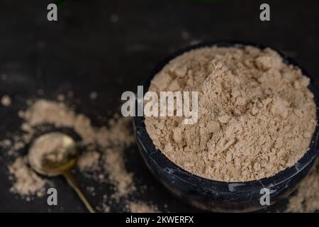 Gros plan de mortier de marbre noir avec Gofio, farine de Canaries à partir de différents grains torréfiés . Ingrédients de la cuisine des îles Canaries. Banque D'Images