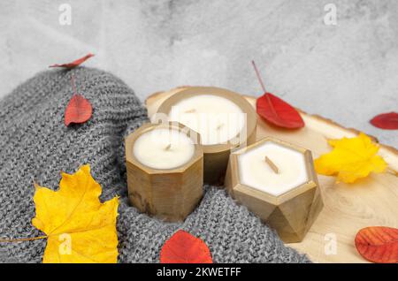 Bougies en pots dorés, feuilles d'automne rouges et jaunes, composition minimale. Le concept de la chaleur et du confort à la maison Banque D'Images