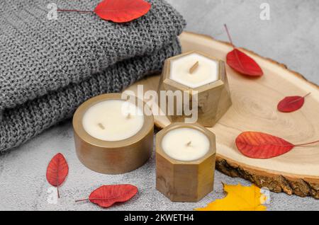 Bougies en pots dorés et feuilles rouges d'automne, composition minimale. Le concept de la chaleur et du confort à la maison Banque D'Images