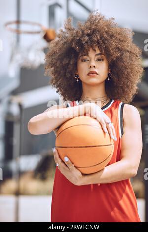 Portrait d'une femme joueur de basket-ball sur un terrain tenant un ballon à l'extérieur et prête pour une compétition sportive. Femme afro-américaine à la mode et sérieuse Banque D'Images