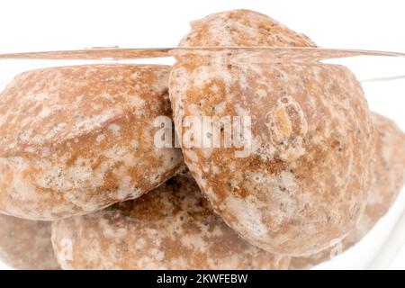 Plusieurs biscuits savoureux de pain d'épice doux dans une plaque de verre, macro, isolé sur fond blanc. Banque D'Images