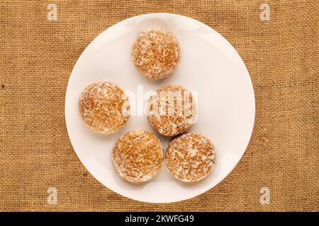 Plusieurs biscuits savoureux de pain d'épice avec des plats de céramique blanche sur toile de jute, macro, vue de dessus. Banque D'Images