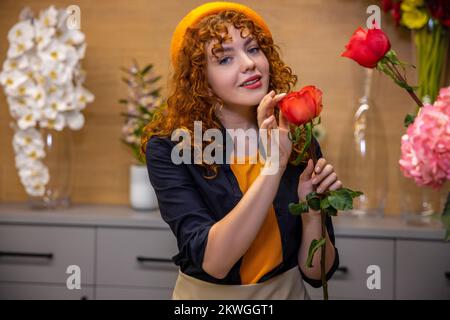 Jeune fille de gingembre en béret dans un fleuriste Banque D'Images