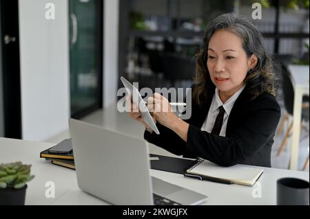 Femme d'affaires asiatique professionnelle et prospère ayant une réunion ou une conférence en ligne avec son équipe, formant ses employés en ligne, en utilisant la Banque D'Images