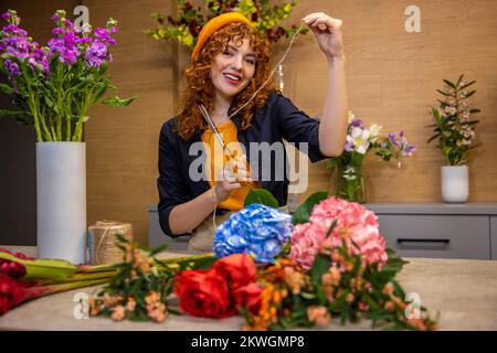 Jeune fleuriste dans un fleuriste traitant de fleurs Banque D'Images