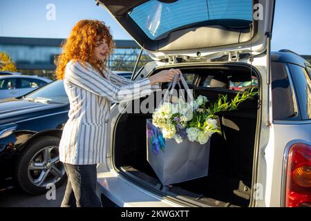 Gingembre jeune femme mettant des sacs dans la voiture Banque D'Images