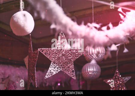 Boules de Noël moelleuses roses avec perles flocons de neige et guirlande accrochées dans la chambre, couleurs roses monochromes. Banque D'Images