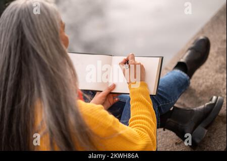 Femme inspirée avec un albom dans les mains sur la rive de la rivière Banque D'Images