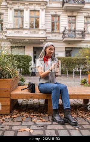 Femme aux cheveux longs assise sur le banc et attendant quelqu'un Banque D'Images