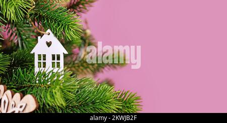 Bannière avec arbre de Noël décoré avec blanc maison en forme d'arbre ornement boules sur fond rose avec espace de copie vide Banque D'Images