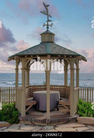 Nuages Puffy verticaux au coucher du soleil Gazebo avec siège et table intégrés dans un beau jardin à la Jolla, Californie. Il y a un sens du vent Banque D'Images