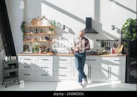 Homme mûr barbu assaisonnement pour une réception dans un livre de cuisine Banque D'Images