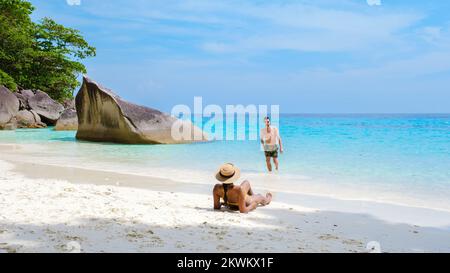 Un couple d'hommes et de femmes se détendant au soleil sur la plage tropicale blanche avec la tourte de couleur océan des îles Similan en Thaïlande. Banque D'Images