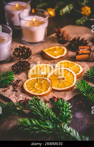 Épices de Noël et d'orange séchées avec branches d'arbre de noël, cannelle, bougies sur la table de cuisine Banque D'Images