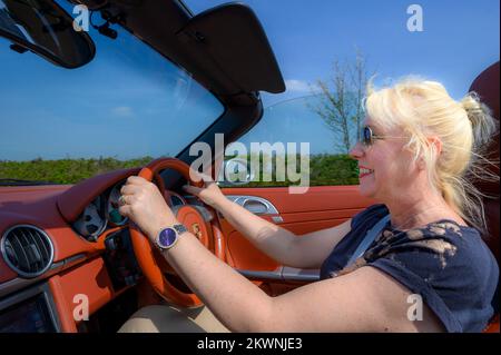 Femme blonde conduisant une voiture de sport Porsche au Royaume-Uni. Banque D'Images