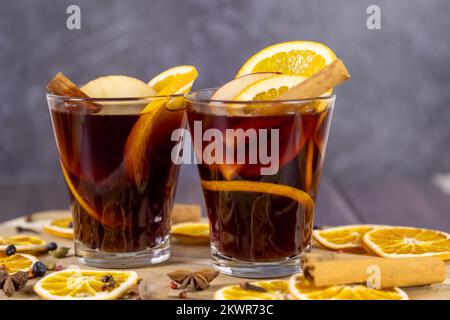 Vin chaud en verre tasses placées sur une table en bois, décorées de fruits secs, vin rouge aromatisé de bâtons de cannelle Banque D'Images