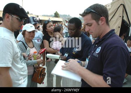 Les feux de forêt, San Diego, Californie, Richard Rabuck, de droite, des relations communautaires de 24 octobre 2007, et José Saint Louis, du centre-droit, ont aidé cette famille Rancho Bernardo qui s'est évacuée pour s'abriter au stade Qualcomm alors que leur maison était menacée par les feux de forêt du sud de la Californie. Michael Raphael/FEMA... Photographies relatives aux programmes, aux activités et aux fonctionnaires de gestion des catastrophes et des situations d'urgence Banque D'Images