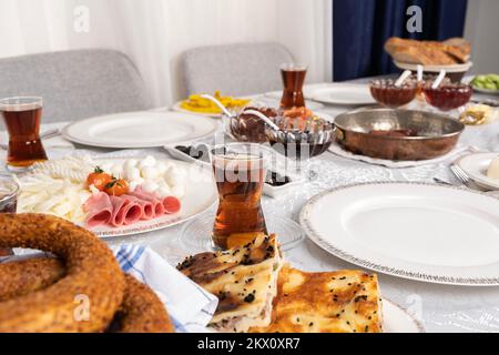 Patty turque appelée su borek et bagel appelé simit sur la table du petit déjeuner. Cuisine turque traditionnelle mais moderne. Verre de thé chaud frais. Banque D'Images