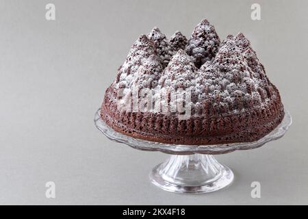 Un gâteau au chocolat de Noël festif. Le gâteau est fait à l'aide d'un moule Bundt pour former la pâte à gâteau dans les formes d'arbre. Une saupoudrez de sucre glace. Banque D'Images