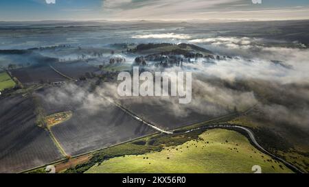 Vue aérienne de Bemersyde depuis Scott's View avec le B6356 bobinage à travers les champs labourés avec une inversion de nuages en novembre. Banque D'Images