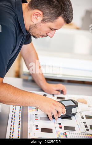 Le spectrophotomètre portable X-Rite vérifie les cellules de couleur, le service prépresse de l'atelier de presse moderne. Banque D'Images