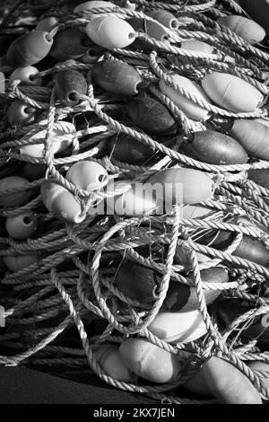 Cordes en nylon avec des bouées de filets de pêche dans une pile sur le front de mer du port de pêche.Photographie noir et blanc. Banque D'Images