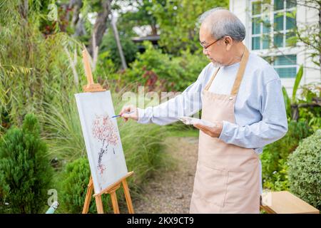 Un vieil homme senior peint des œuvres d'art à l'aide d'un pinceau et d'une peinture à l'eau sur toile Banque D'Images