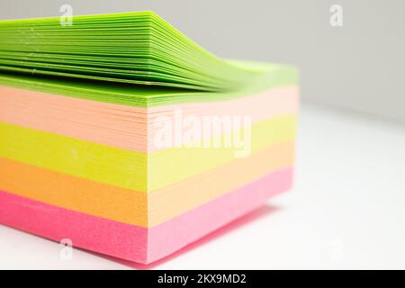 Les autocollants post-it multicolores s'empilent sur fond blanc, gros plan flou Banque D'Images