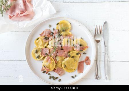 Pâtes fourrées au jambon italien, au beurre et aux graines de citrouille grillées sur une assiette Banque D'Images