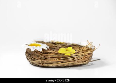 Arrière-plan de Pâques. Panier de paille de nid avec fleurs décoratives, pour oeufs de Pâques. Banque D'Images