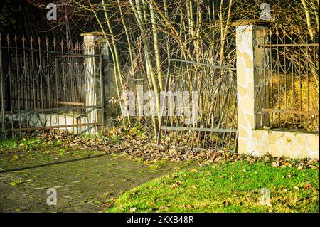 porte d'entrée brisée abandonnée et clôture métallique à tête de fer, image légèrement teintée Banque D'Images